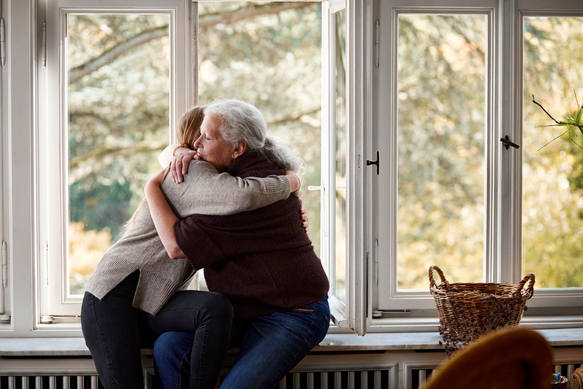 Two women hugging by the window
