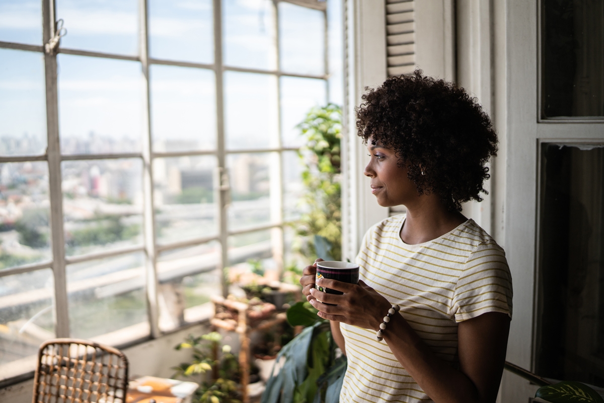 Women looking out the window holding a mug