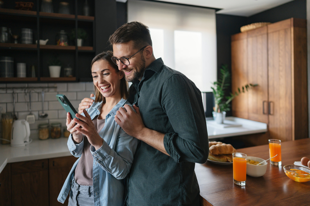 Man and women looking at a phone in the kitchen