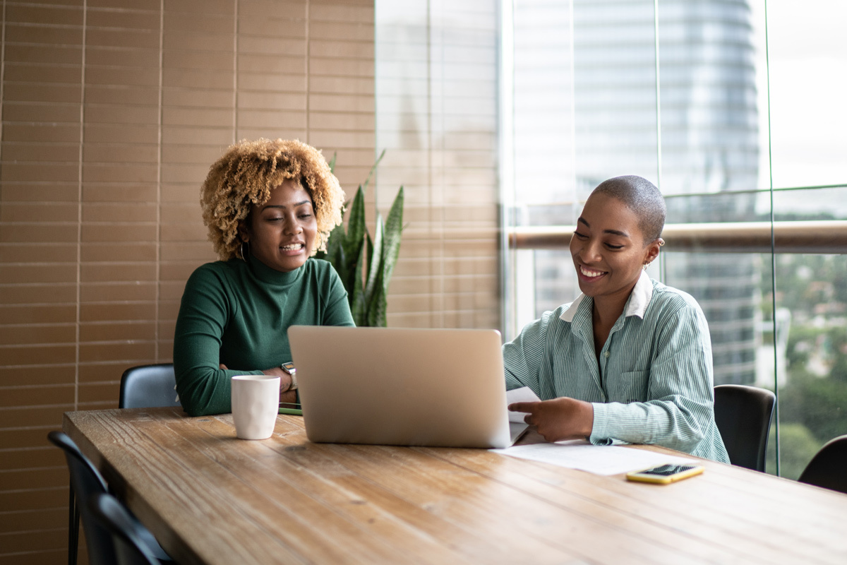 Two business women looking at a laptop chatting