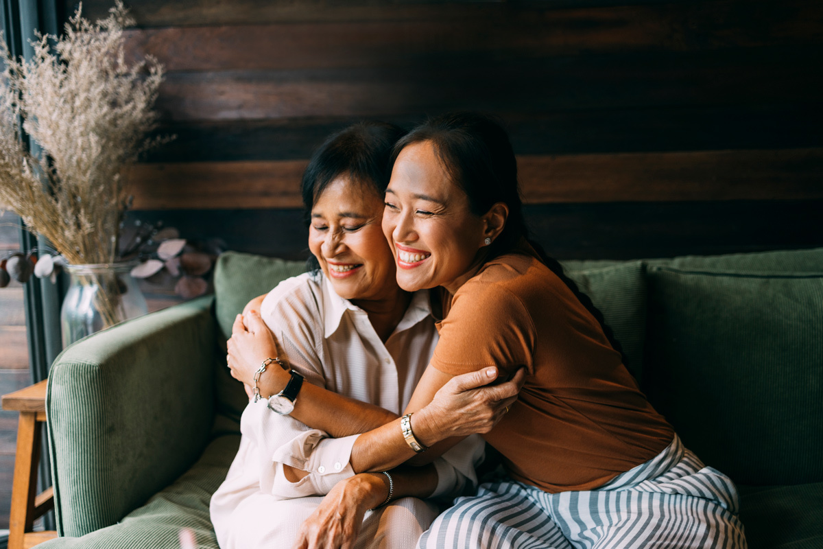 Two women hugging sitting on a sofa