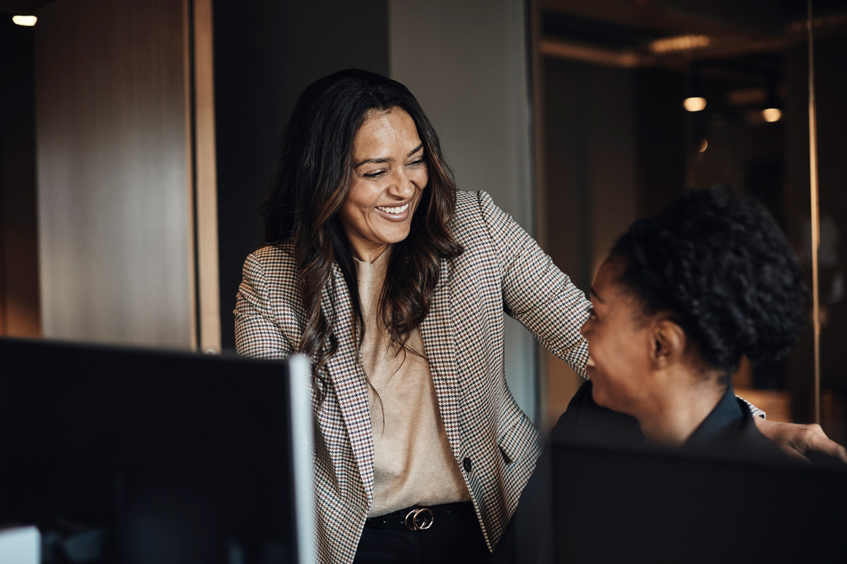 Two business women laughing looking at a screen