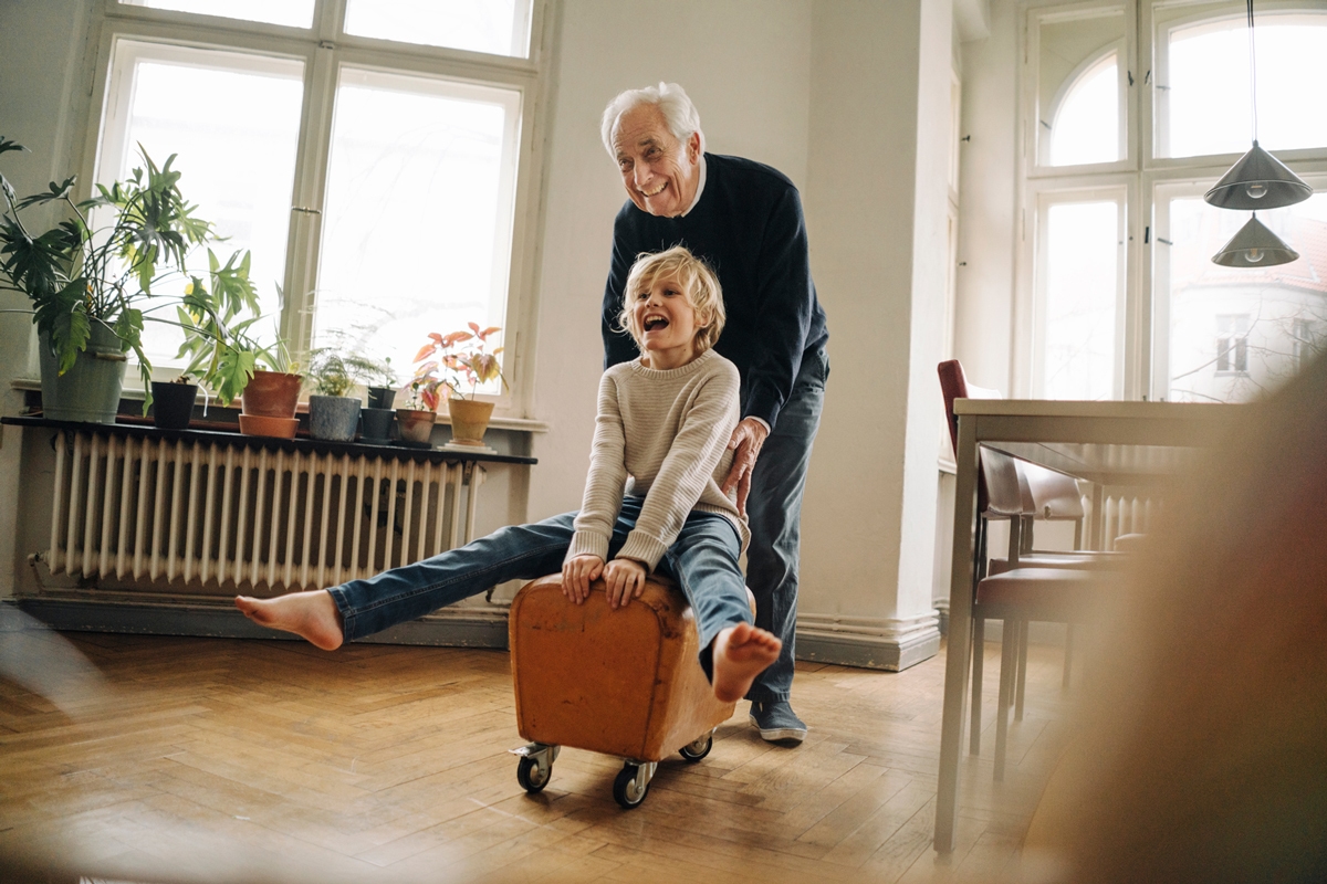 Grandfather pushing grandson on a stool laughing