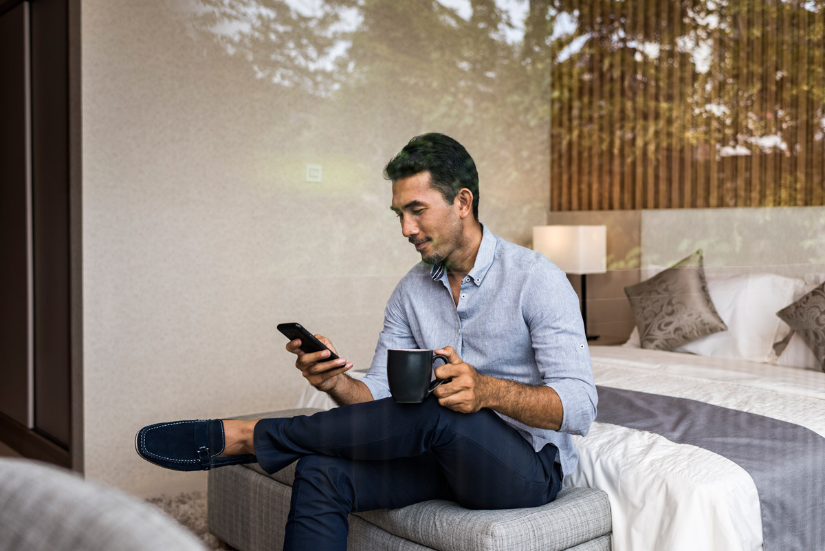 Man sitting on the end of his bed looking at his phone
