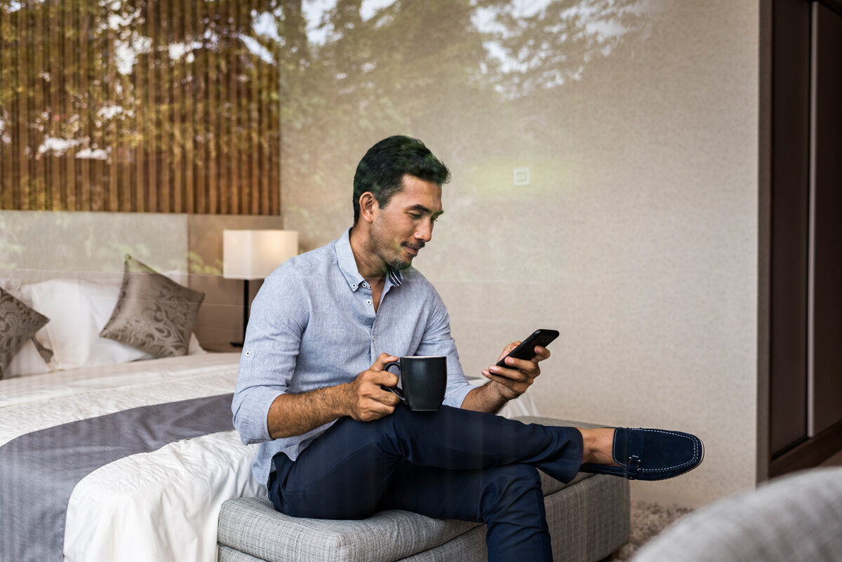 Man sitting on the end of his bed looking at his phone