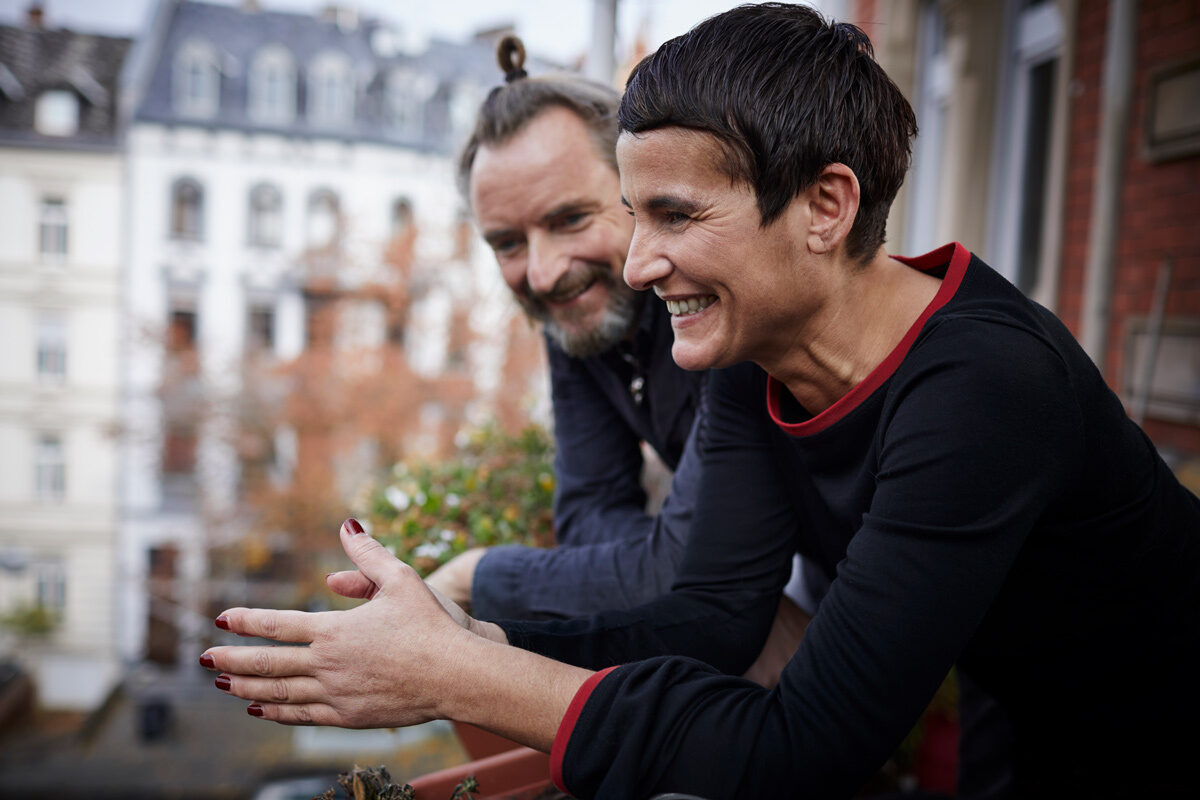 Man and women standing on a balcony laughing