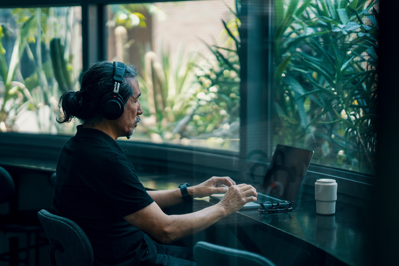 Man looking at his laptop with headphones on in a cafe