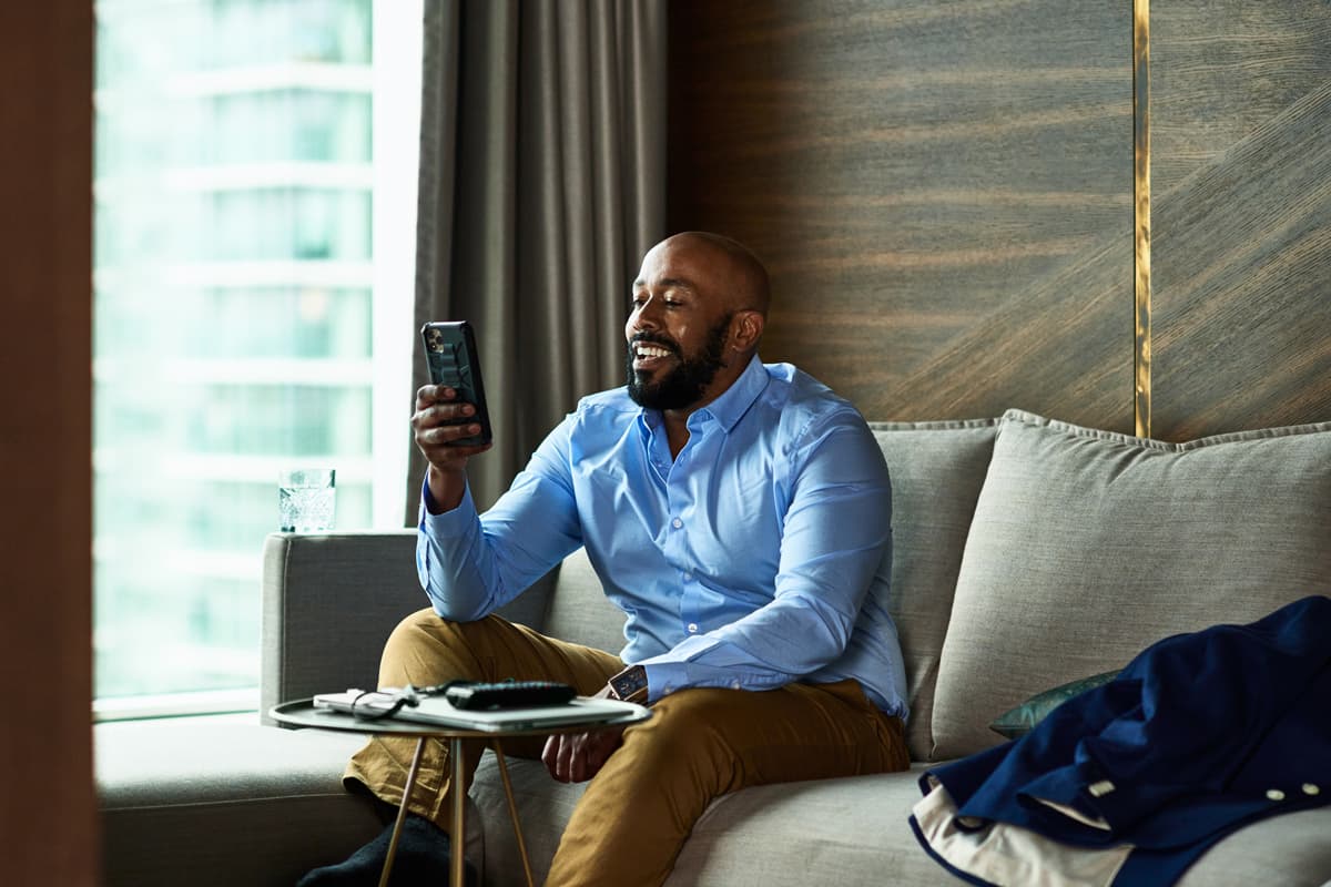 Man sitting on the sofa looking at his phone smiling