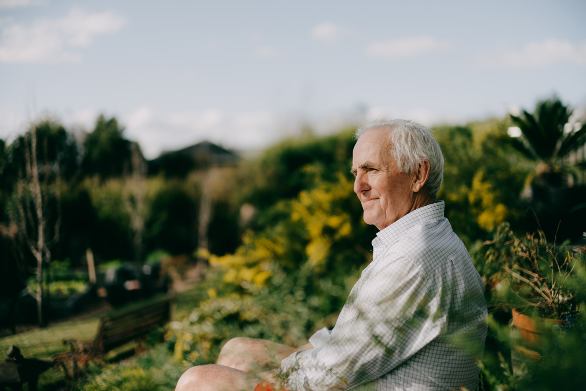 Senior man sitting in the park smiling
