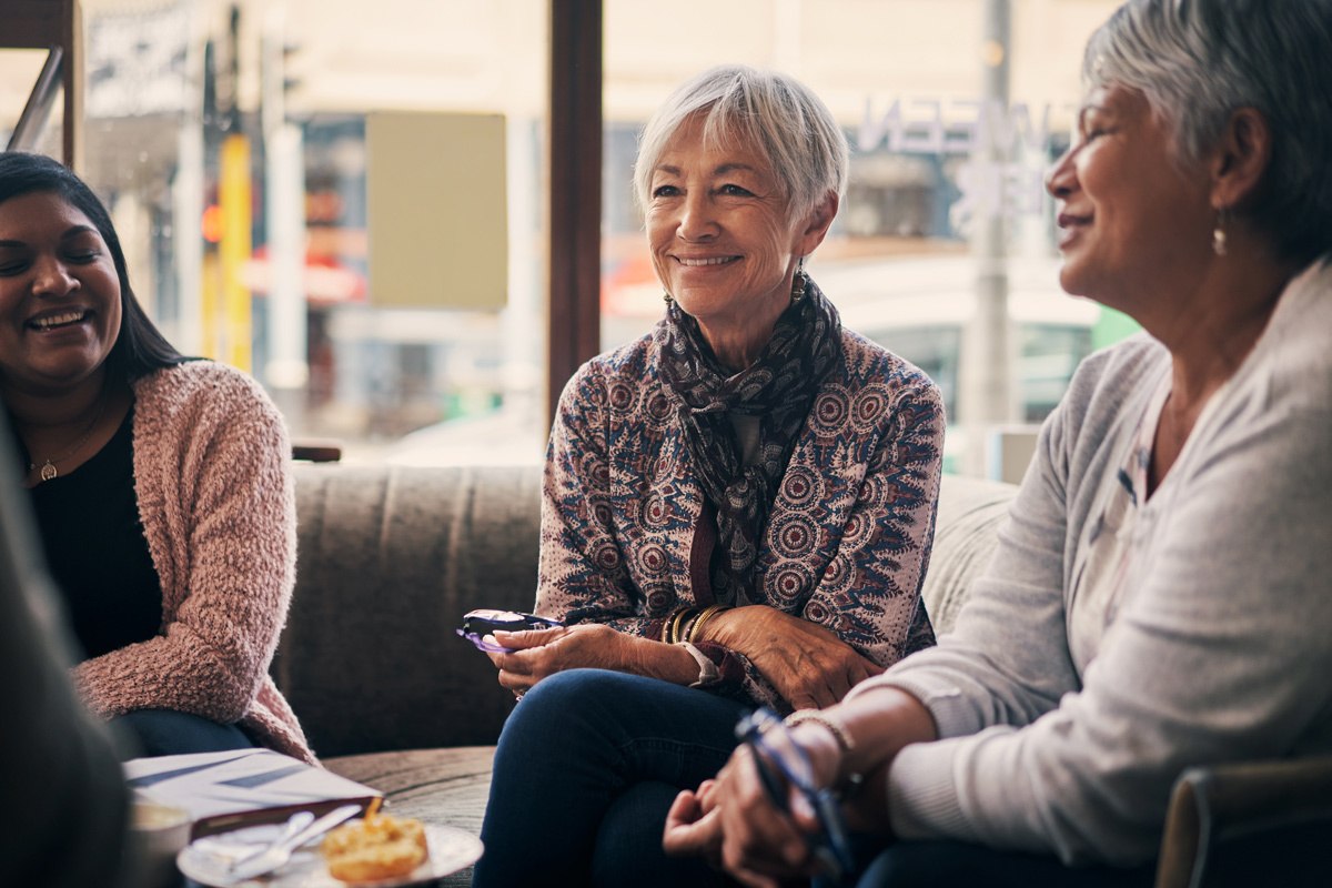 Three women sitting laughing in a cafe