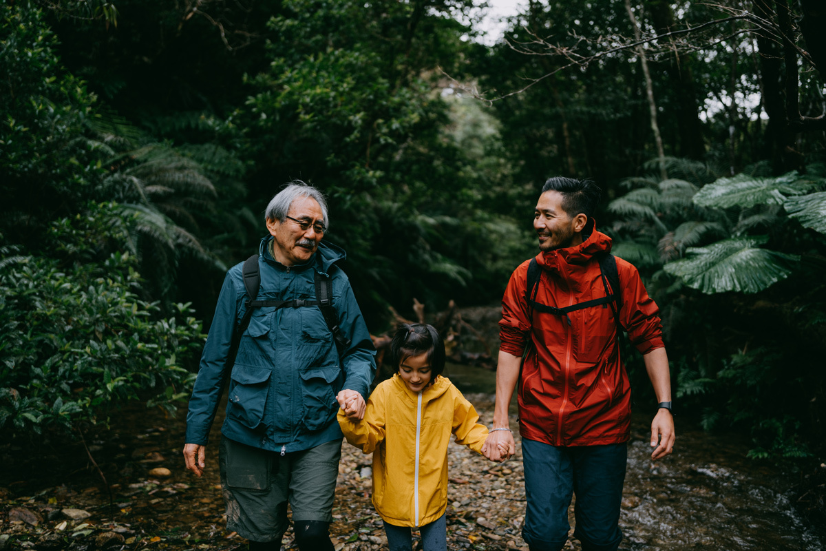 Two men and one girl walking through the woods smiling