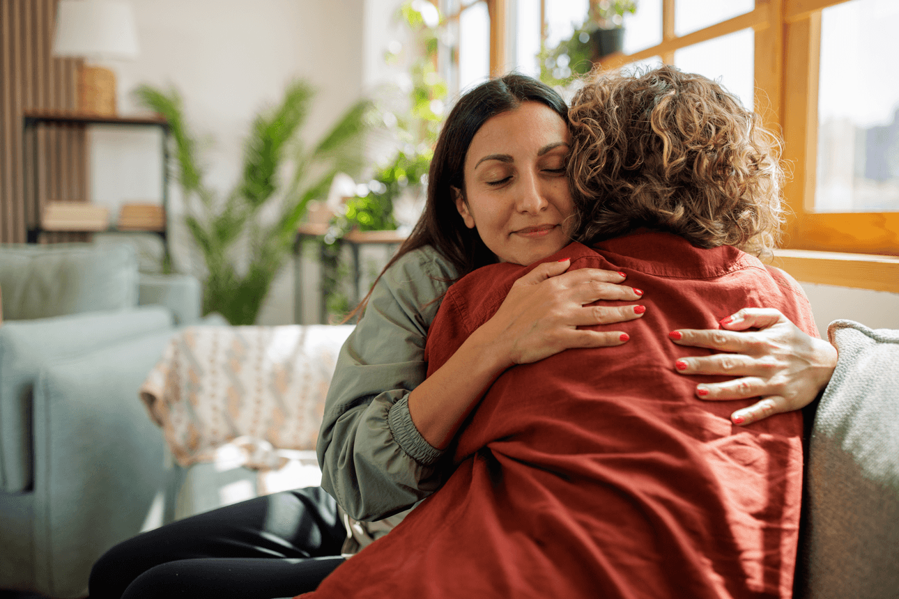 Two women hugging sitting on the sofa