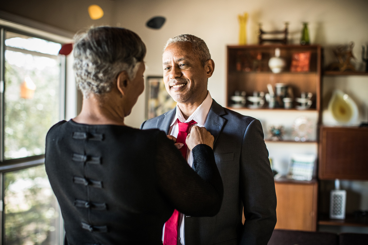 Women helping tie mans tie