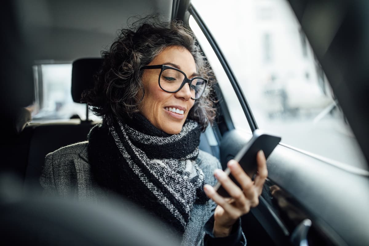 Women sitting in back of the car looking at her phone
