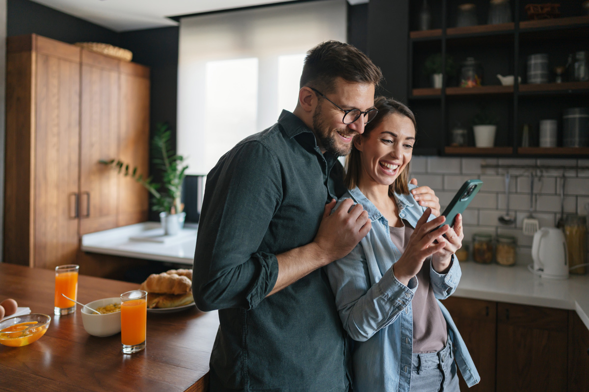Young man and women looking at her phone in the kitchen
