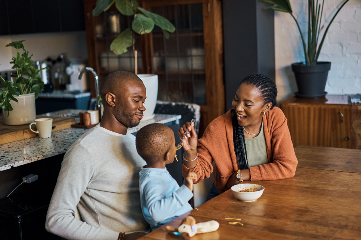 Family sitting in the kitchen whilst mum feeds child