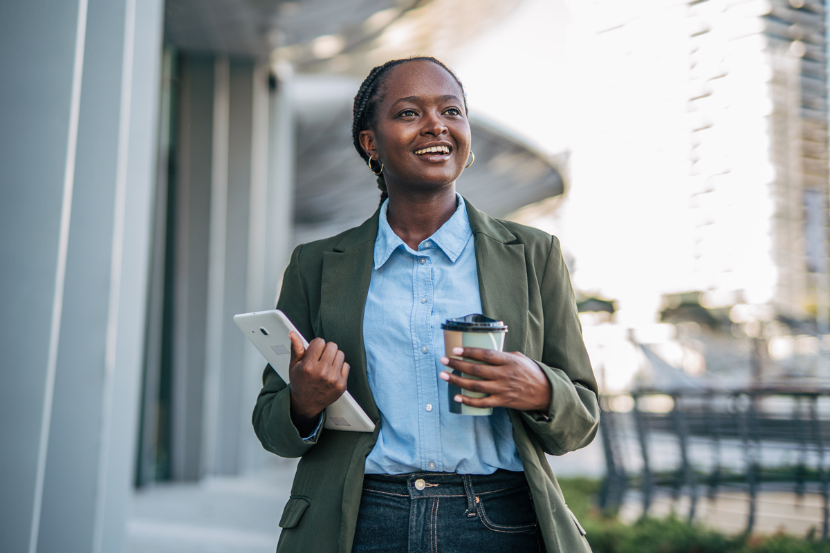 Women walking outside with a take away drink and her tablet